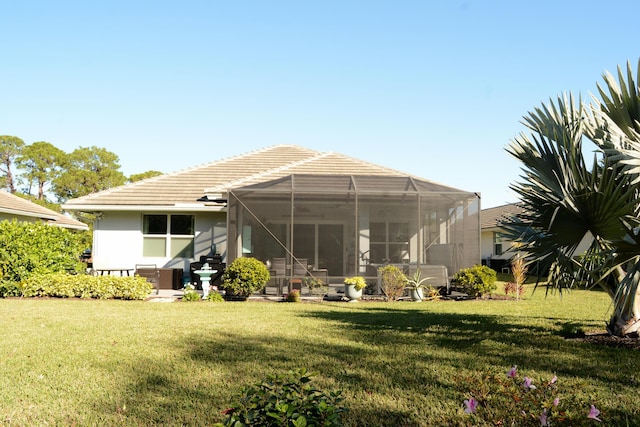 rear view of house featuring a lanai and a lawn