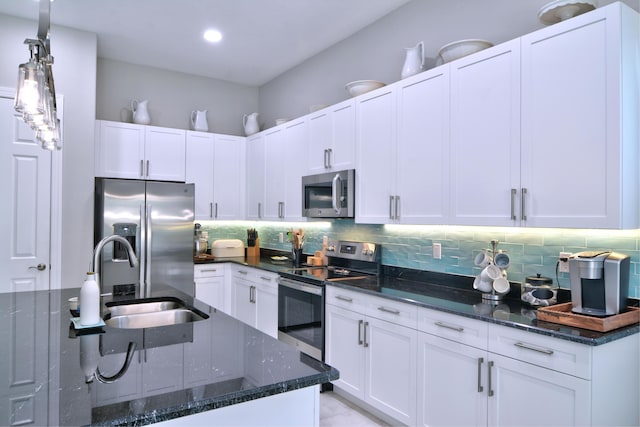 kitchen featuring white cabinetry, sink, stainless steel appliances, and dark stone counters