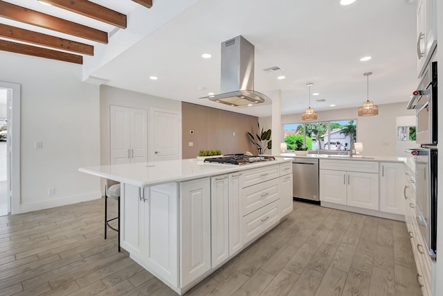 kitchen with appliances with stainless steel finishes, a center island, island range hood, pendant lighting, and white cabinets