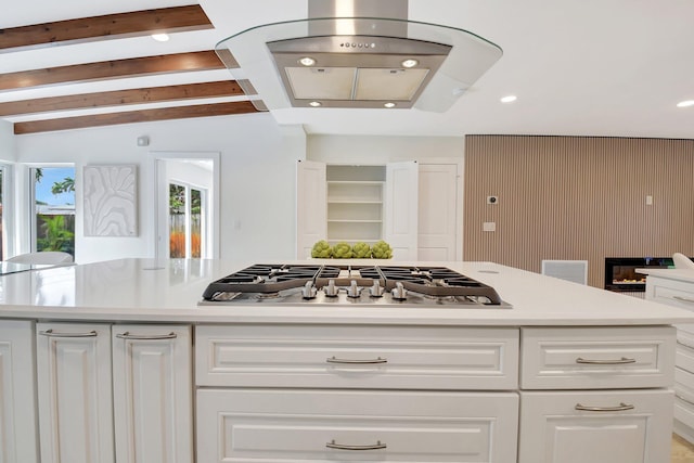 kitchen with white cabinetry, a kitchen island, beam ceiling, and stainless steel gas stovetop