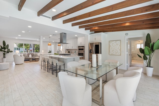 dining space featuring beam ceiling and light hardwood / wood-style flooring