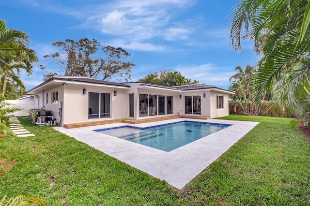 rear view of property with a patio, a lawn, and a fenced in pool