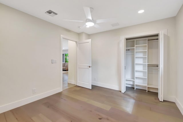 unfurnished bedroom with hardwood / wood-style flooring, ceiling fan, and a closet