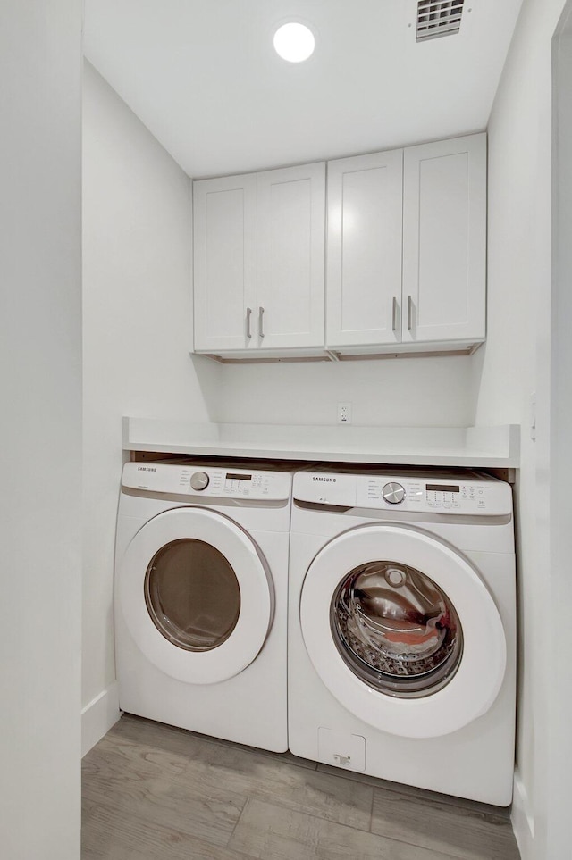 laundry room with cabinets, independent washer and dryer, and light hardwood / wood-style floors