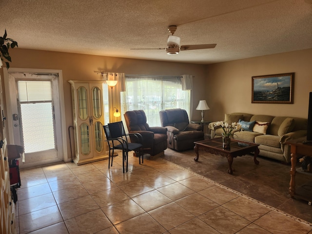 living room featuring ceiling fan, a textured ceiling, and light tile patterned flooring