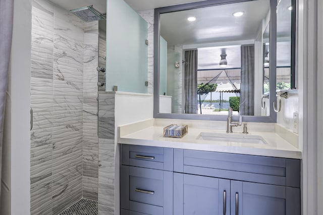 bathroom with tiled shower and vanity