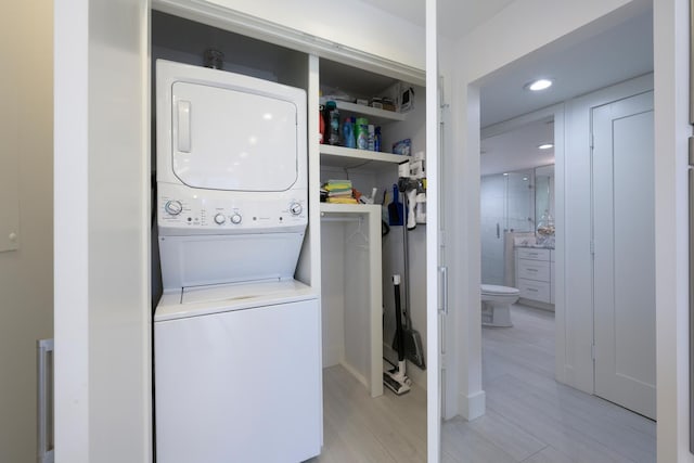 laundry area with stacked washer / drying machine and light hardwood / wood-style floors