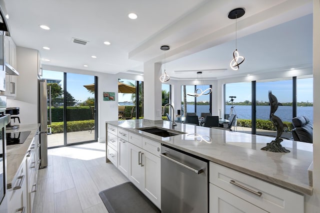 kitchen featuring pendant lighting, sink, appliances with stainless steel finishes, light stone counters, and white cabinets