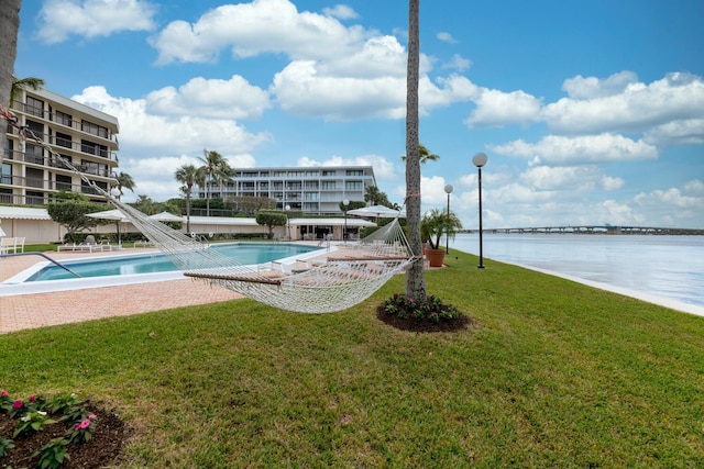 view of swimming pool with a lawn and a water view