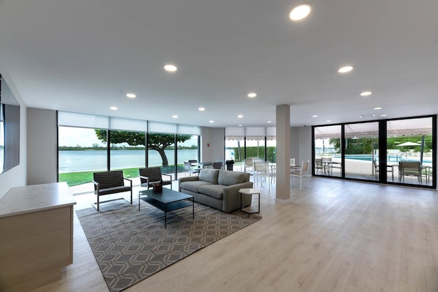 living room featuring a water view, floor to ceiling windows, and light hardwood / wood-style floors