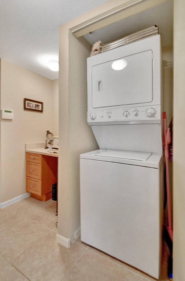 clothes washing area with light tile patterned floors and stacked washing maching and dryer