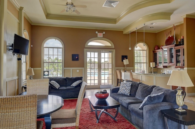 living room with a tray ceiling, ornamental molding, tile patterned floors, and ceiling fan