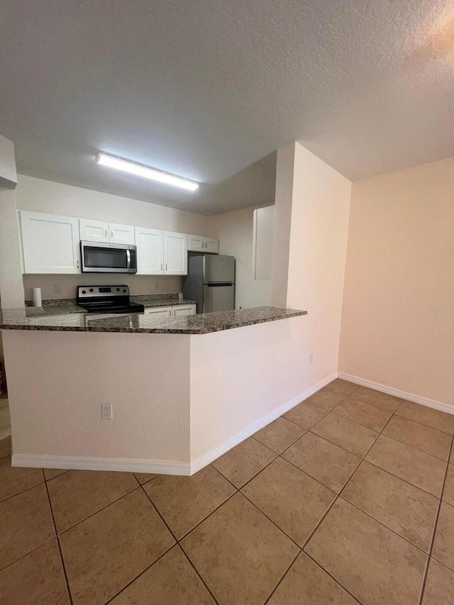 kitchen featuring light tile patterned flooring, stainless steel appliances, kitchen peninsula, and white cabinets