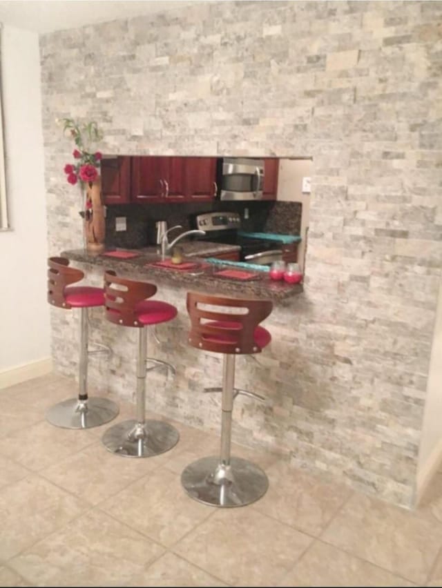 kitchen featuring stainless steel appliances, a breakfast bar, and light tile patterned flooring