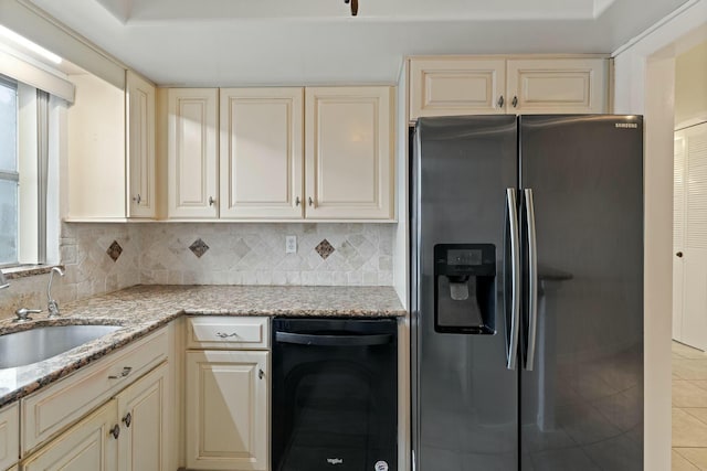 kitchen featuring stainless steel fridge with ice dispenser, cream cabinets, light stone countertops, and sink