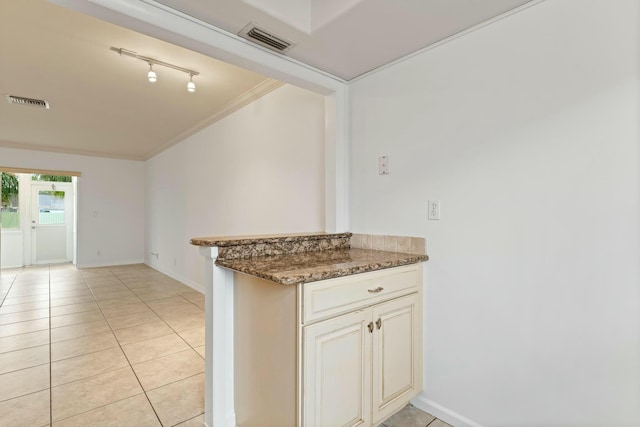 kitchen with crown molding, light tile patterned floors, and dark stone countertops