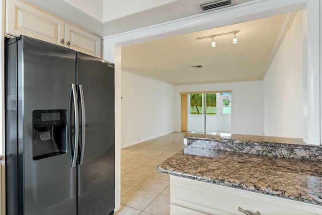 kitchen with stainless steel refrigerator with ice dispenser, ornamental molding, dark stone counters, and light tile patterned floors