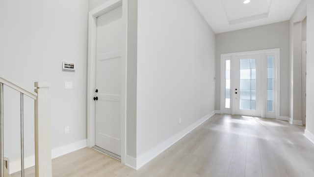 entryway with a raised ceiling and light wood-type flooring