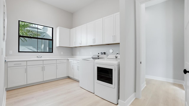 laundry room featuring cabinets, sink, independent washer and dryer, and light wood-type flooring