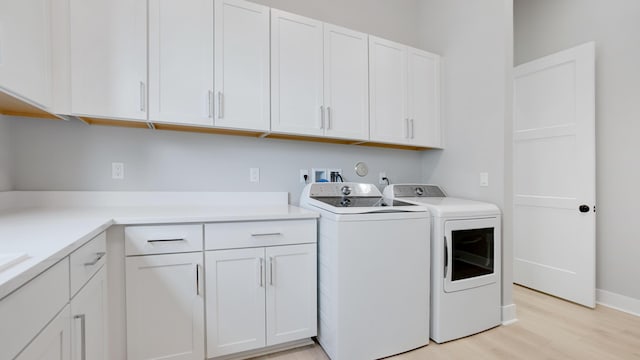 laundry room featuring cabinets, independent washer and dryer, and light wood-type flooring