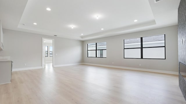 empty room featuring light wood-type flooring and a tray ceiling