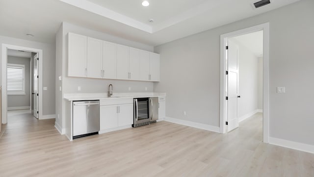 kitchen with wine cooler, sink, white cabinetry, light wood-type flooring, and dishwasher