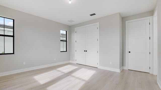 unfurnished bedroom with light hardwood / wood-style flooring and a closet