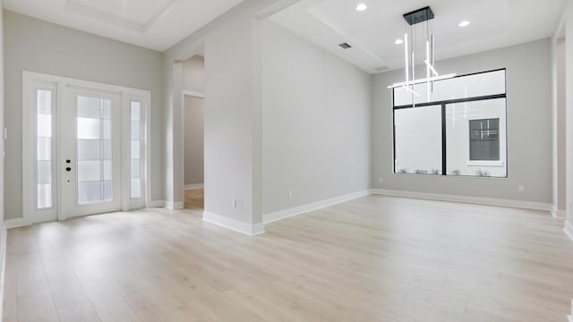 interior space with a tray ceiling and light hardwood / wood-style floors