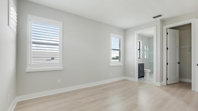 unfurnished bedroom with light hardwood / wood-style flooring, a closet, and ensuite bathroom