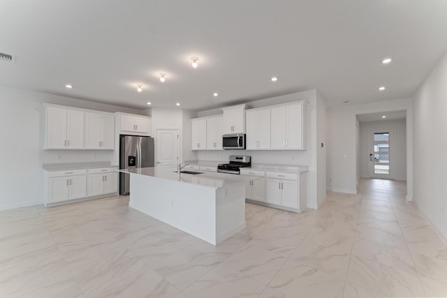 kitchen featuring stainless steel appliances, a kitchen island with sink, sink, and white cabinets