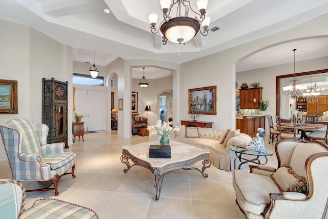 tiled living room featuring a raised ceiling and a notable chandelier