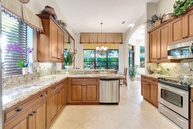 kitchen with pendant lighting, tasteful backsplash, sink, stainless steel appliances, and an inviting chandelier