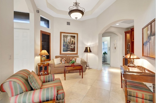 interior space with a tray ceiling, light tile patterned flooring, and a high ceiling