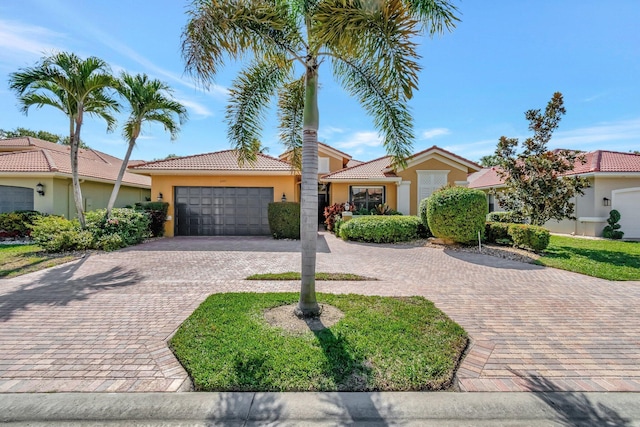 view of front of house with decorative driveway, a tile roof, an attached garage, and stucco siding
