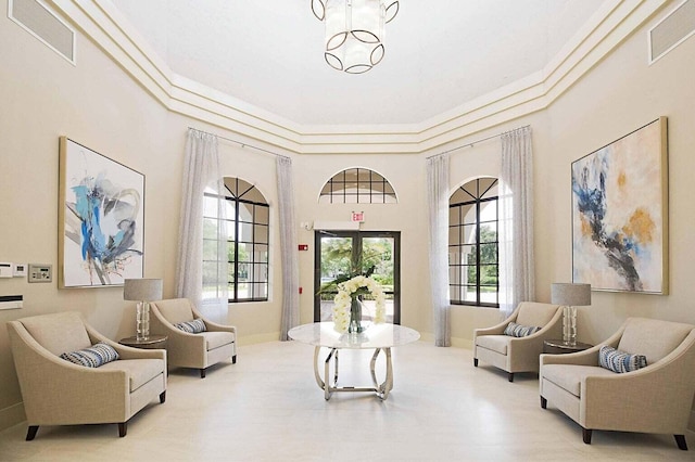 living area with visible vents, baseboards, an inviting chandelier, and crown molding