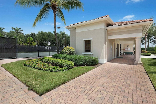 exterior space featuring a tennis court and fence