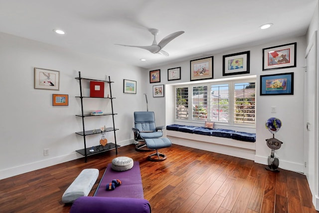 living area featuring dark wood-type flooring and ceiling fan