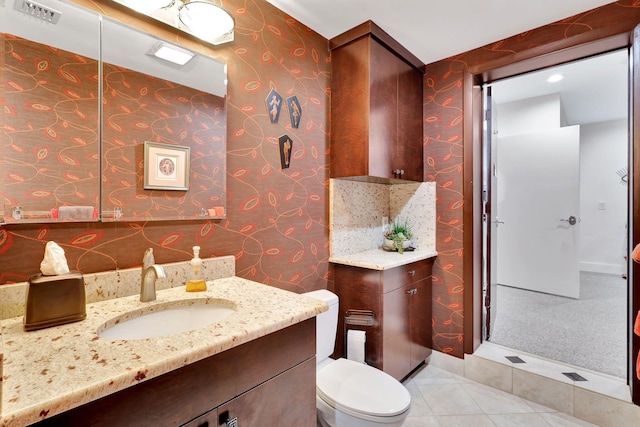 bathroom featuring tile patterned flooring, vanity, toilet, and walk in shower