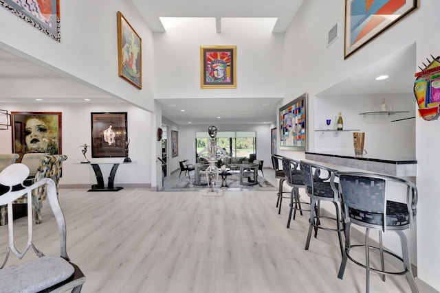 bar featuring light hardwood / wood-style flooring and a high ceiling