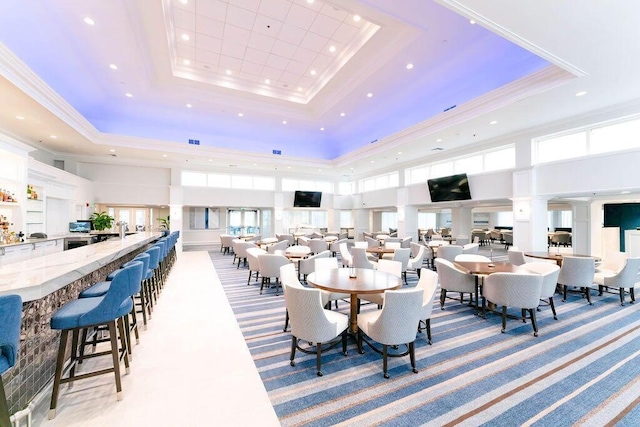 carpeted dining area featuring a high ceiling, ornamental molding, and a tray ceiling