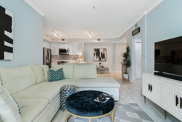 living room with ornamental molding, rail lighting, a textured ceiling, and light hardwood / wood-style floors