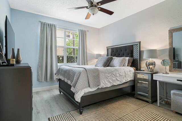 bedroom with ceiling fan, light hardwood / wood-style flooring, and a textured ceiling