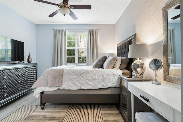 bedroom with light wood-type flooring, a textured ceiling, and ceiling fan