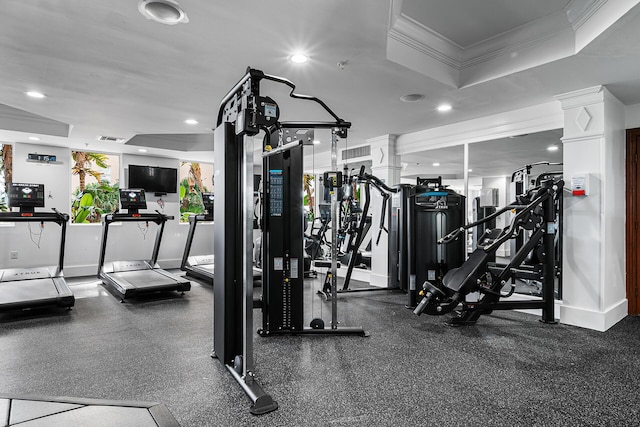 gym featuring crown molding, decorative columns, and a raised ceiling