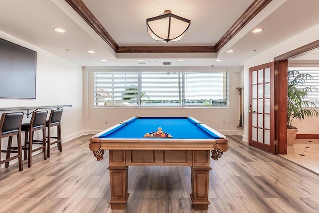 game room featuring crown molding, a raised ceiling, and light wood-type flooring