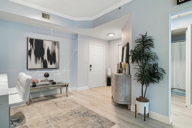 foyer entrance featuring crown molding and light hardwood / wood-style floors