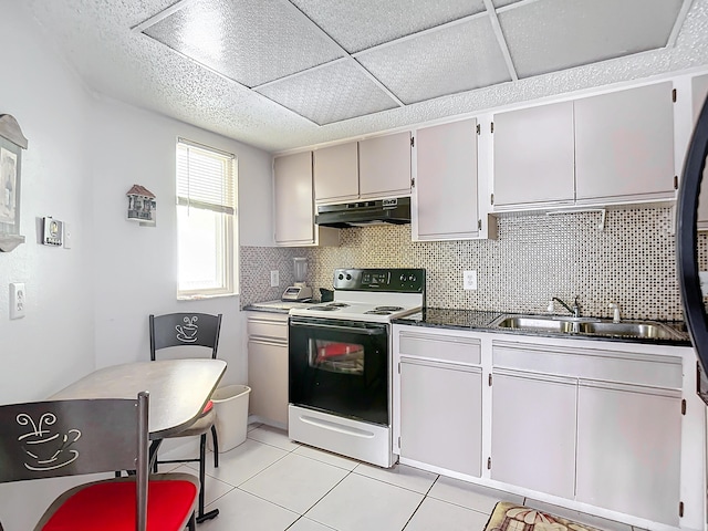 kitchen with sink, light tile patterned floors, backsplash, electric range, and a drop ceiling