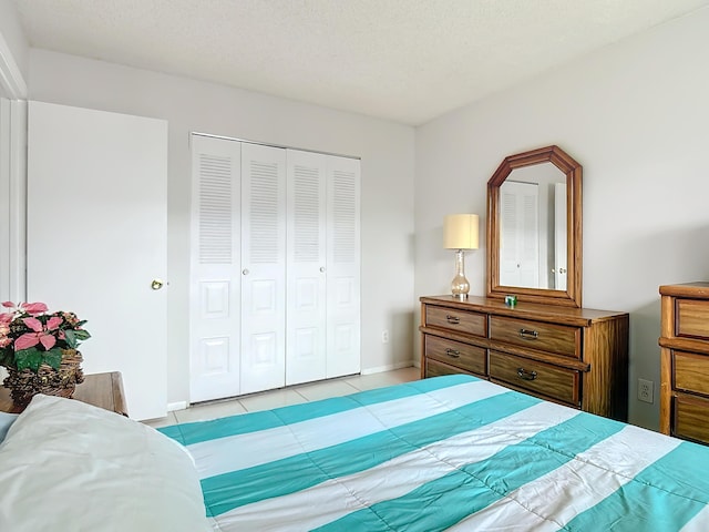 bedroom with a closet, a textured ceiling, and light tile patterned flooring