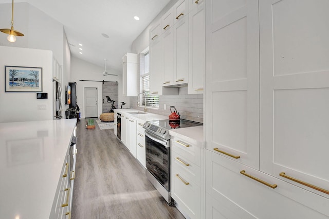 kitchen featuring stainless steel electric range oven, vaulted ceiling, hanging light fixtures, light hardwood / wood-style floors, and white cabinets