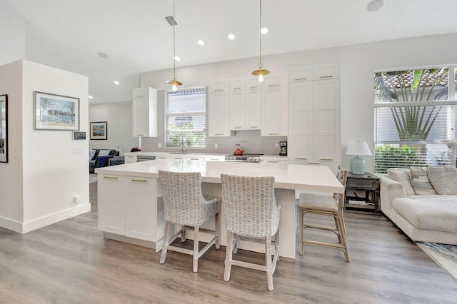 kitchen featuring a large island, decorative light fixtures, white cabinetry, and light wood-type flooring